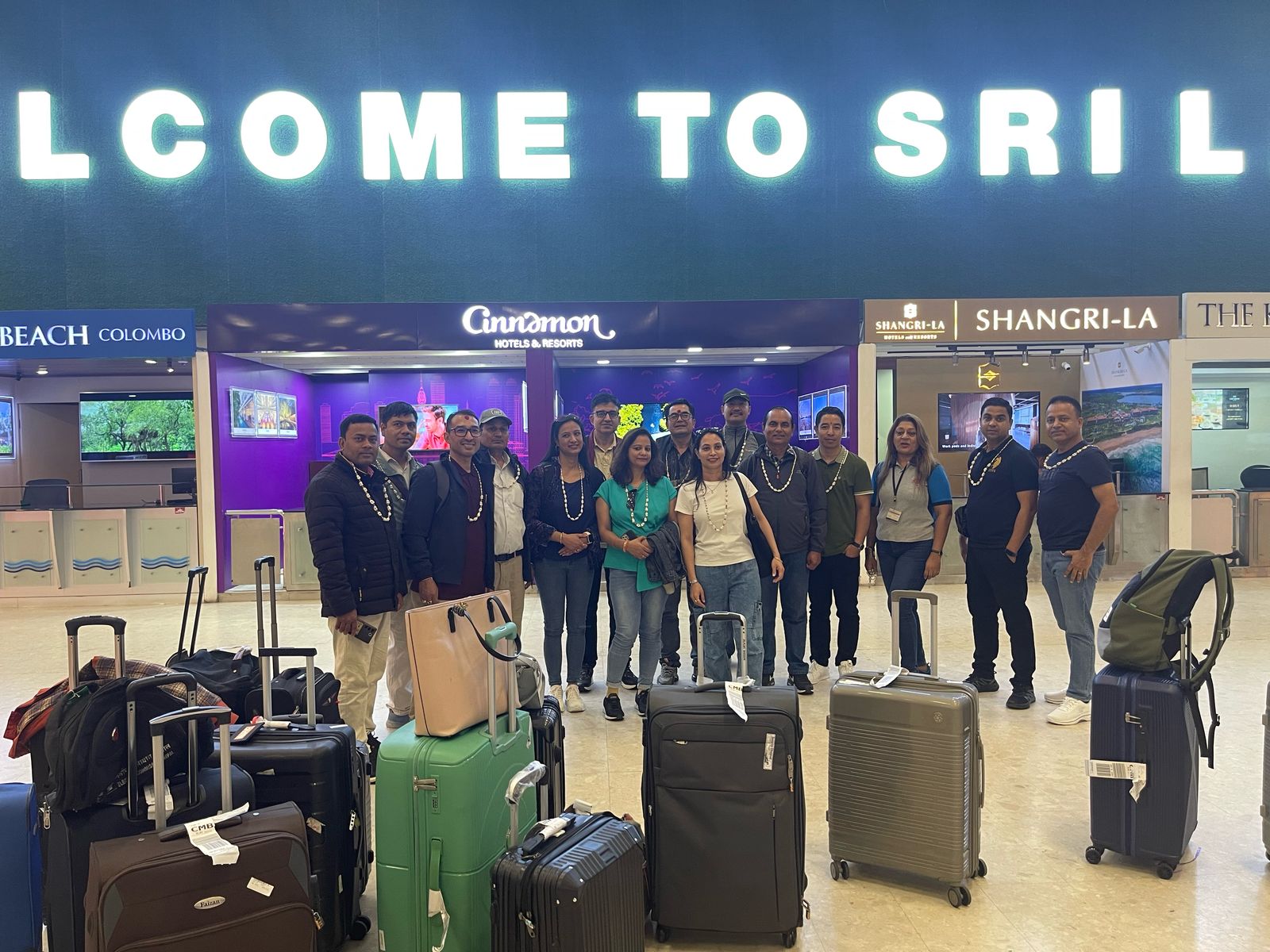 Tour group with luggage under the Welcome to Sri Lanka sign at the airport
