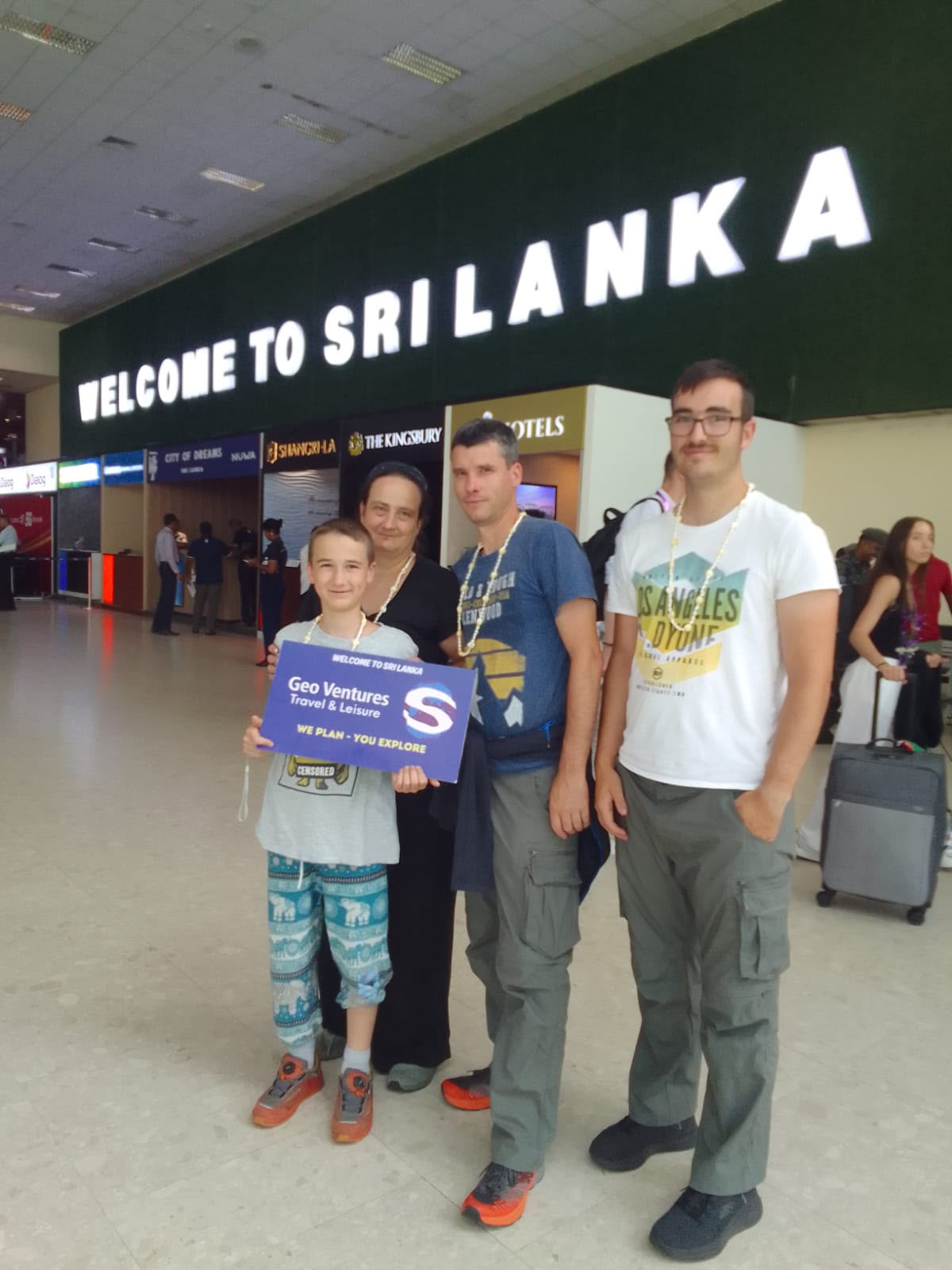 Family welcomed at the airport with flower garlands and a Geo Ventures sign