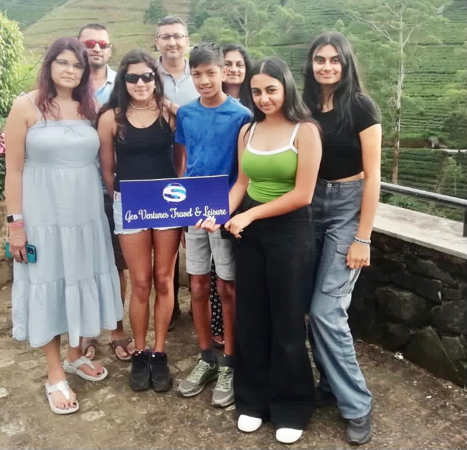 Family holding a Geo Ventures sign in front of tea plantations
